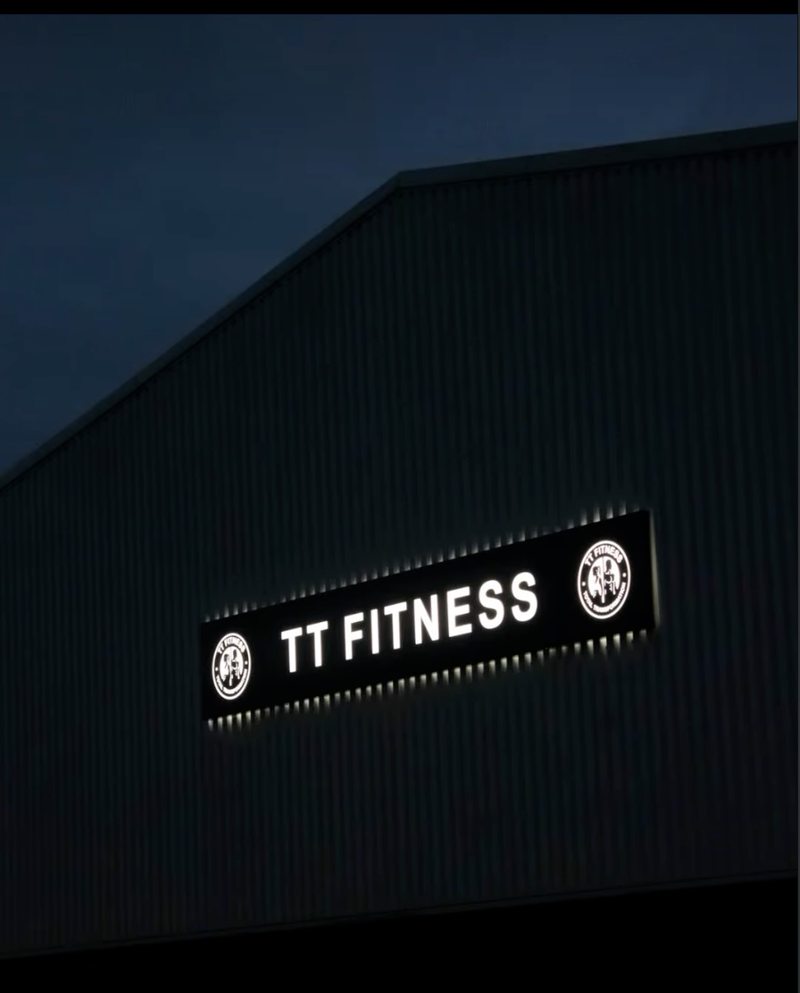 The illuminated TT Fitness sign on the gym exterior on Southfields Drive